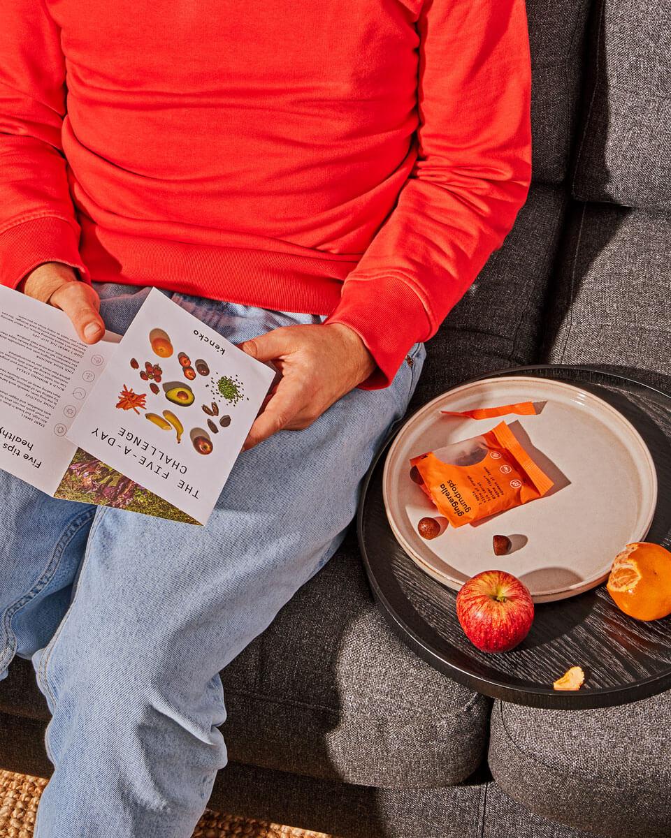 A person holding and reading a menu, with a small assortment of fruit snacks placed next to them on the table